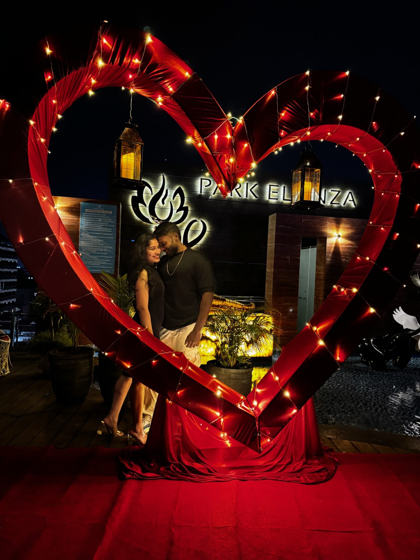Aster and Chris together inside a glowing red heart of lights, where it began